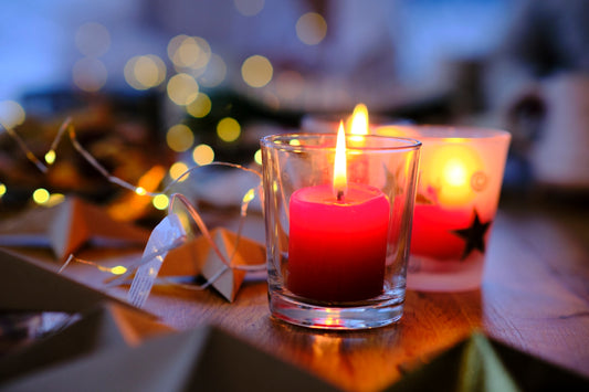 two lit candles sitting on a table next to a box