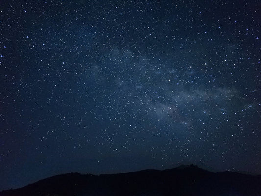 the night sky is filled with stars above a mountain