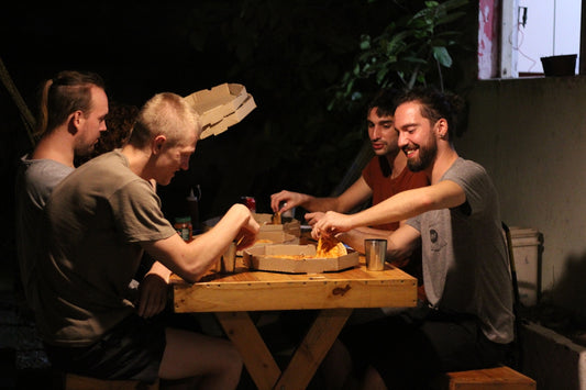 four men eating beside table