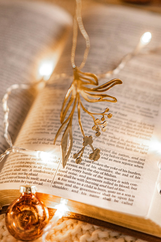 an open book with a christmas ornament hanging from it