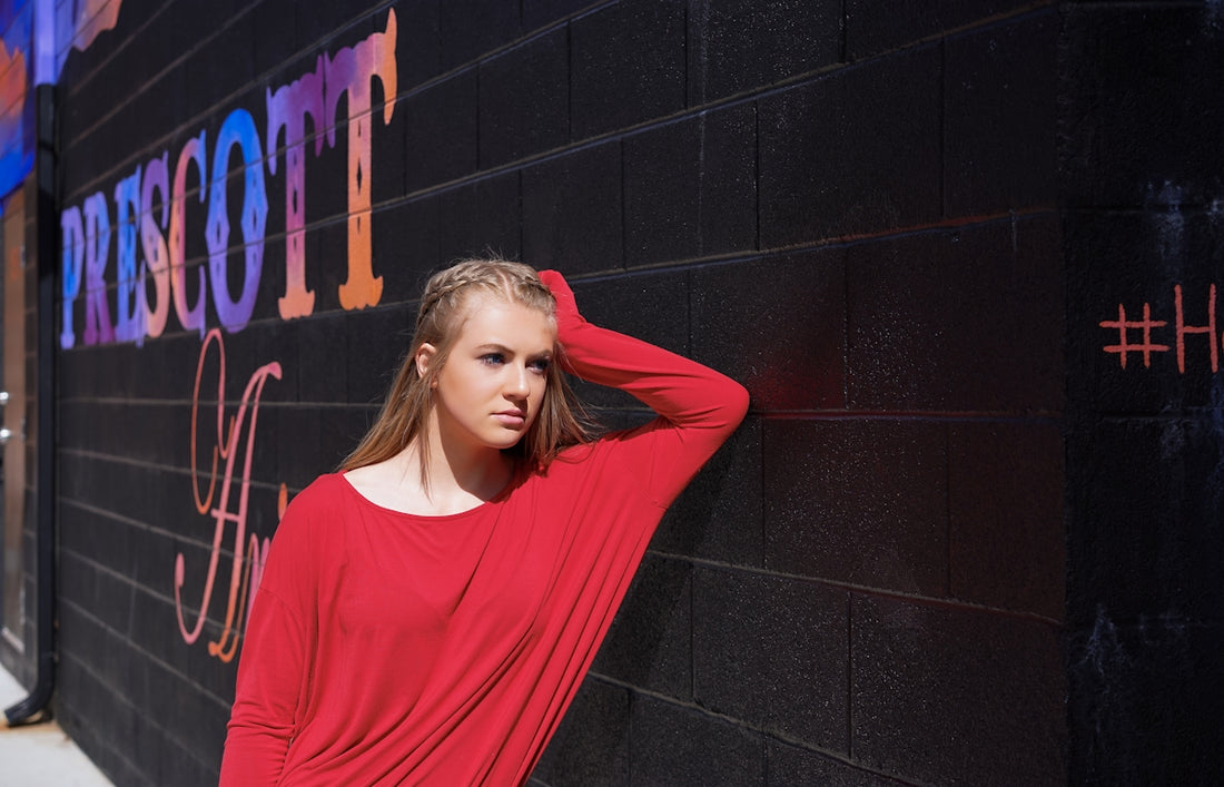 a woman leaning against a wall with her hand on her head