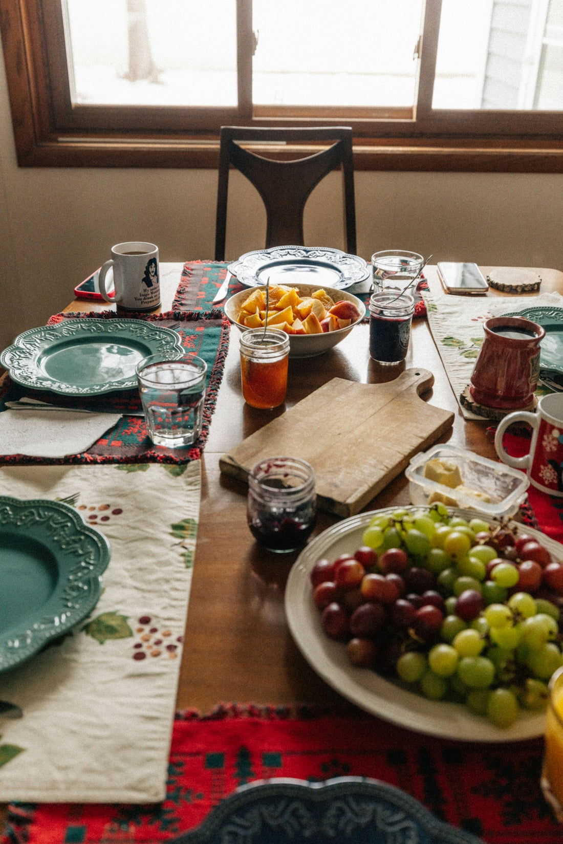 Table set with fruit, drinks, and dishes for a meal.